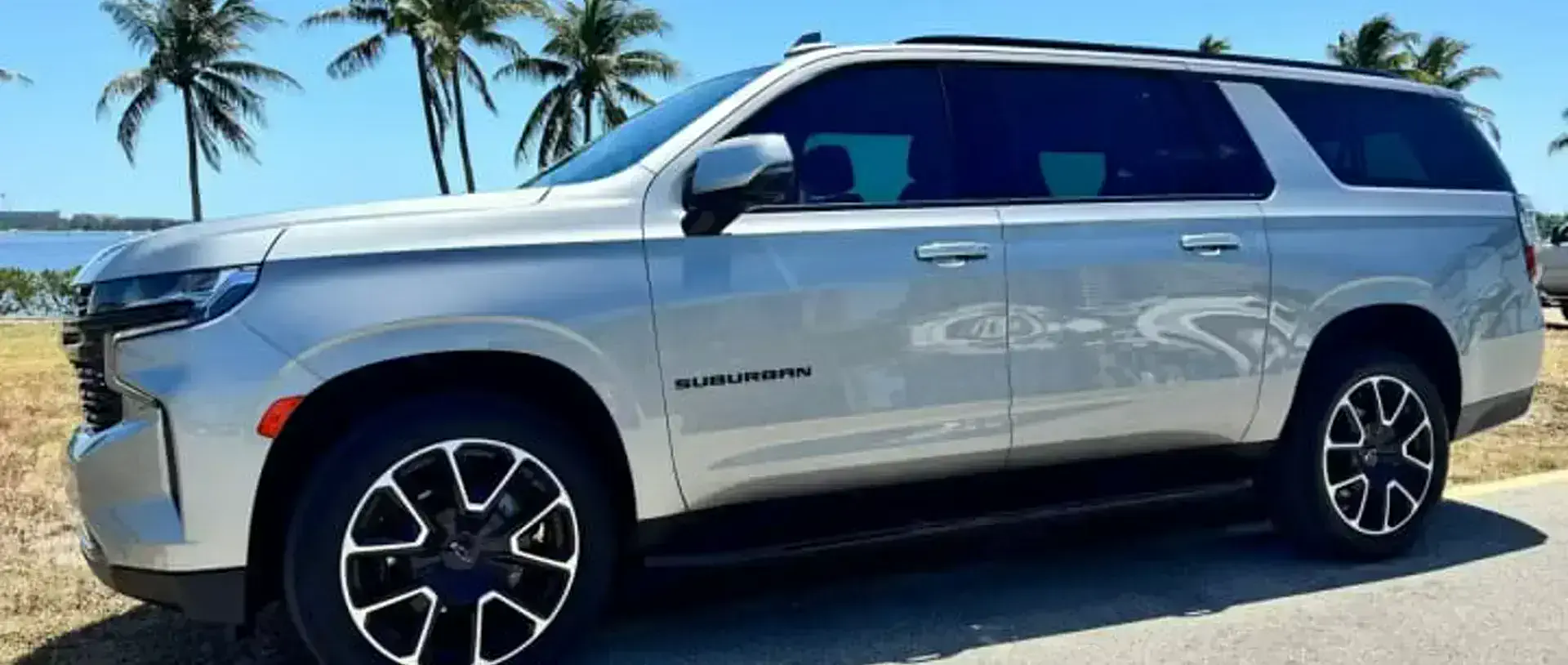 A 2023 Chevrolet Suburban from the SWFL Auto Rentals fleet on a coastal road in Southwest Florida